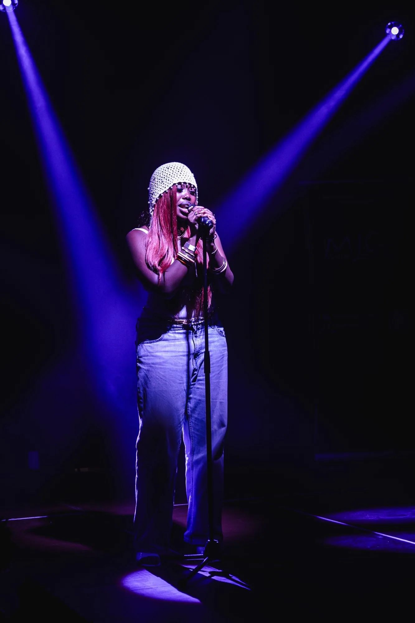 Chanteuse au micro sur scène sous des projecteurs violets