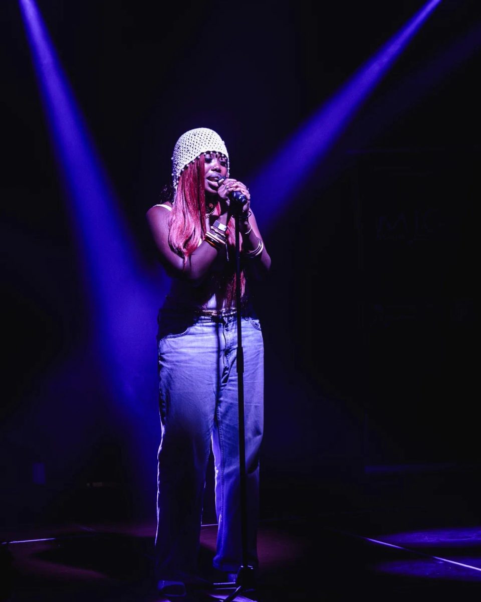 Chanteuse au micro sur scène sous des projecteurs violets